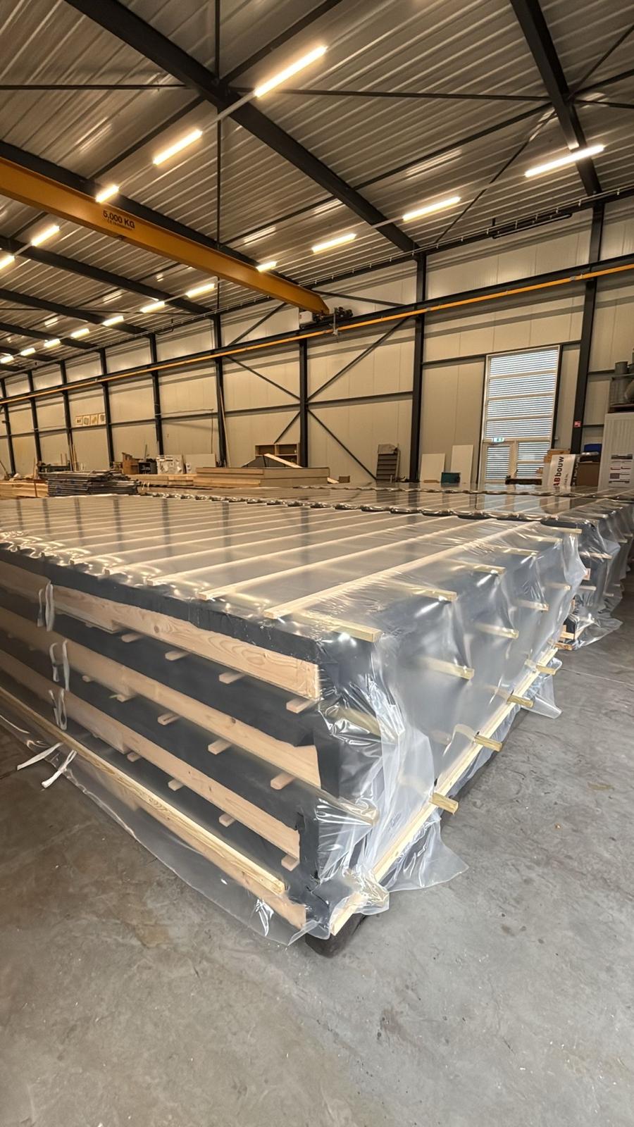 Ingepakte prefab elementen onder de kraanbaan in de eigen productiehal
